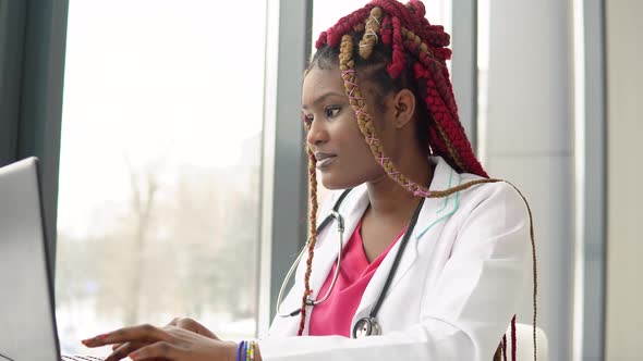 Young African American Female Doctor Working on Laptop in Modern Clinic alt