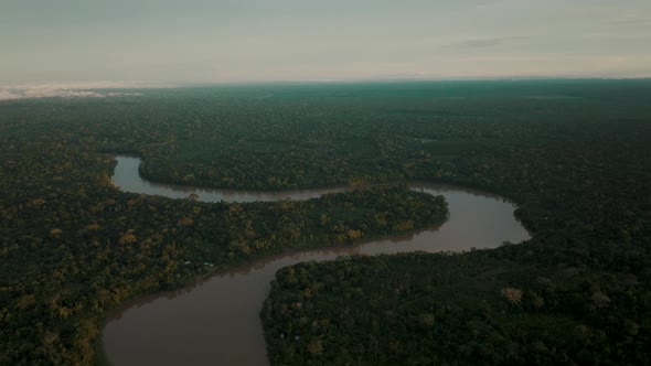 River snakes through vast tropical rainforest landscape; panoramic aerial alt