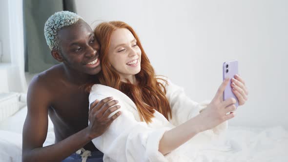 International Young Couple in the Early Morning Communicates By Video Link Newlyweds on Vacation