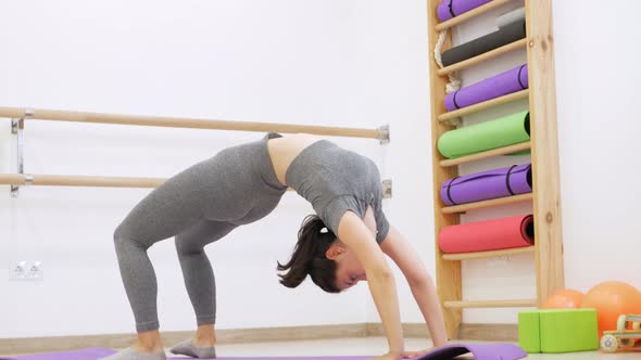 Woman Makes Bridge with Vertical Twine Legs Gymnast in Gym