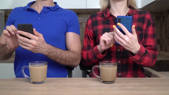 Young Couple Family Man and Woman with Smartphones at Home in the Kitchen alt