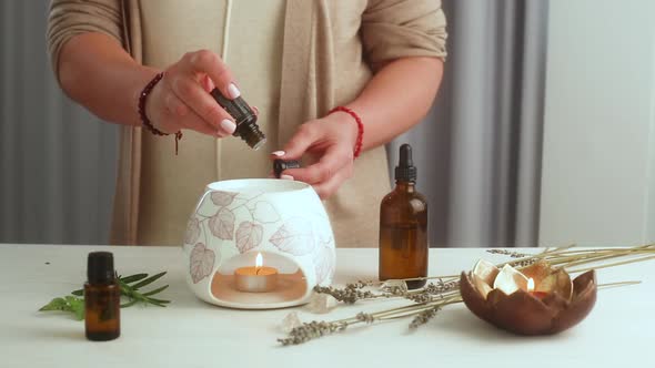 Home SPA concept. Woman prepares an aroma lamp and pour into a water