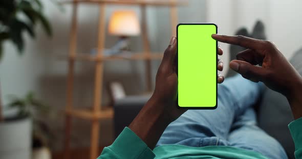 African American Guy Scrolling News Feed and Looking at Smartphone Mock Up Screen, Man Browsing Net alt