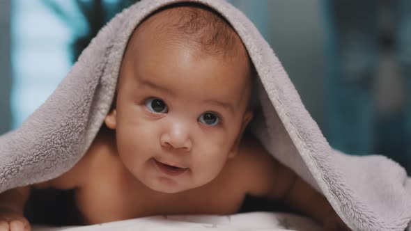 Close Up of Cute Black Baby with Head Covered with Fluffy Towel alt