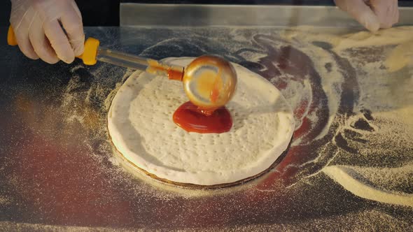 Chef Spreading Tomato Sauce on Pizza Dough alt