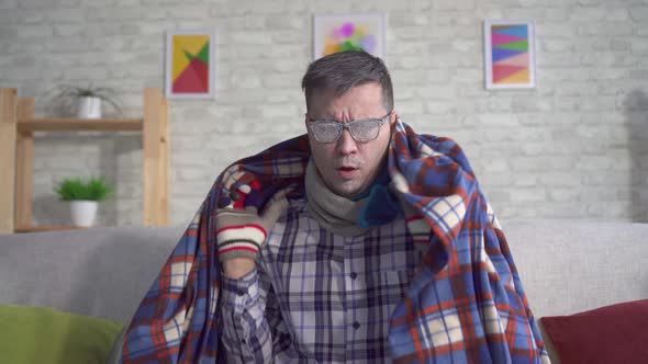 Frozen Man Covered in Frost Wrapped in a Blanket with Gloves in the Living Room and Looks in the alt