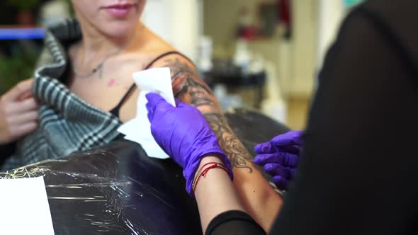 Tattoo artist tattooing an arm alt