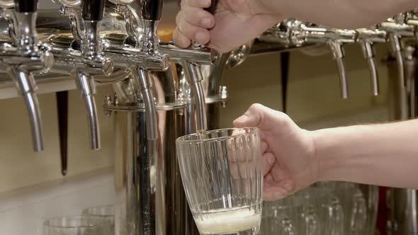 Barman Is Pouring Beer From Tap Into Big Glass Mug in Pub in Evening