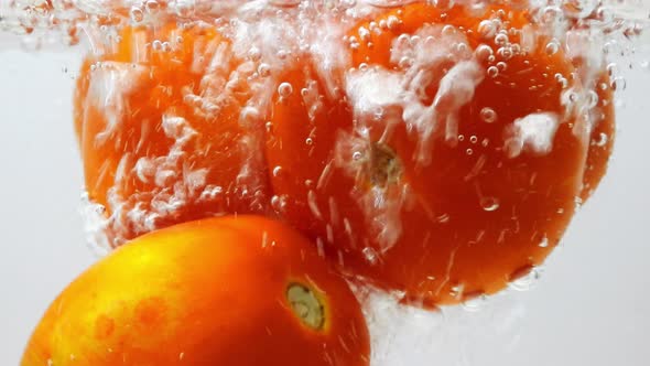 Pouring water into tomatoes in a glass pot. Static, close up alt