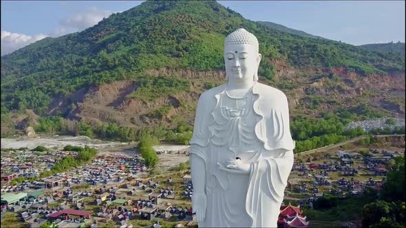 Closeup Flycam Shoots Buddha Statue Against Landscape alt