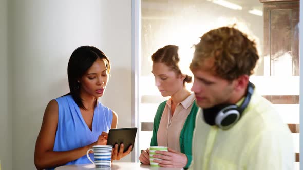 Businesspeople discussing over digital tablet alt