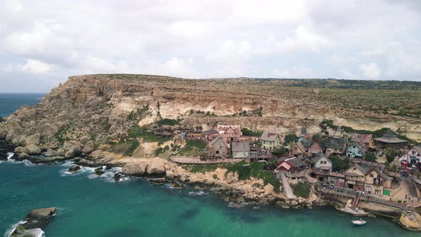 Aerial shot of Popeye village of Malta settle just near the sea in the rocky cliff. View of the famo alt