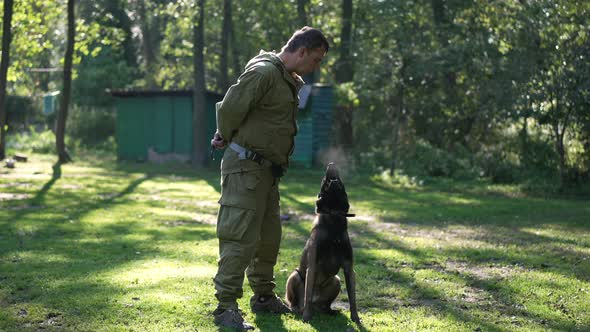 Wide Shot Dog Barking in Slow Motion with Professional Male Cynologist Spitting Looking at Camera alt