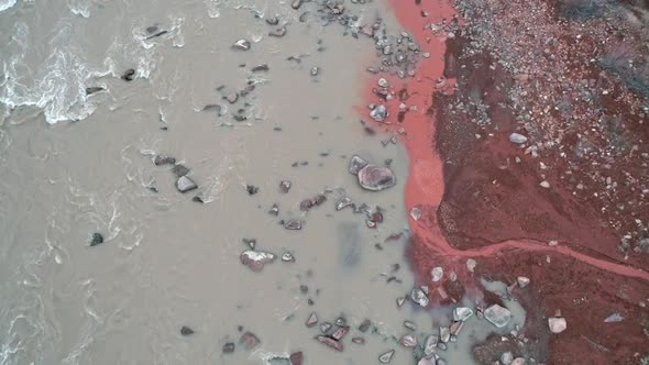 Aerial view of red sandy stream merging with the Colorado River alt