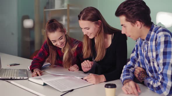 Happy Students Working on Their Homework Sitting Together at the Table and Drinking Coffee alt