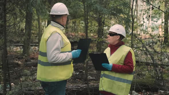 Man and Woman Ecologist in Workwear Against Background of Garbage in Forest