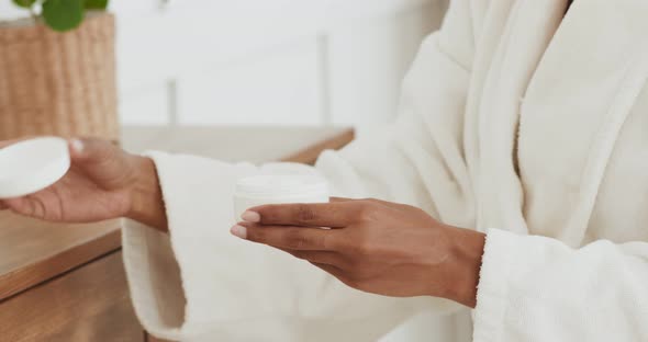 Close Up Shot of Black Woman Opening Jar with Moisturizing Cream and Taking It, Slow Motion alt
