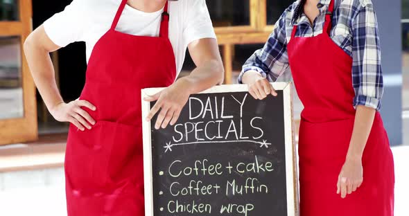 Waiter and waitresses standing with menu board alt