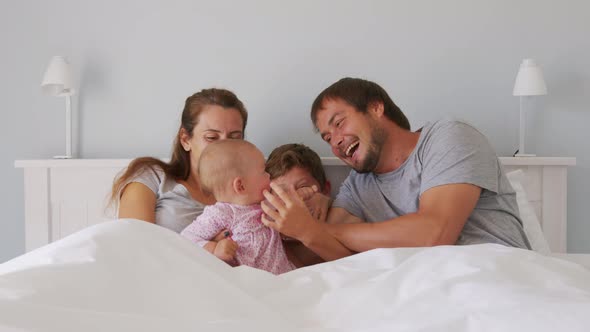 Happy Family with Cute Little Kids Son Daughter Tickling Having Fun Relax on Bad Together Young alt