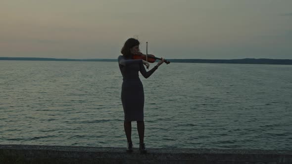 Woman Is Playing Violin Near Lake