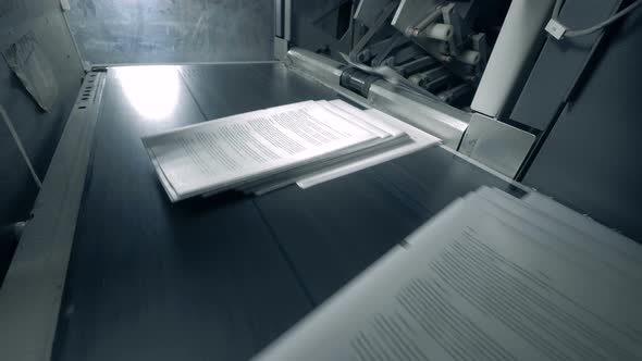 Pages of Printed Paper Are Moving Along the Conveyor. alt