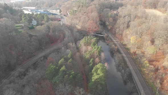 Railway Along Water Canal Autumn Scene Barren Forest Backward Aerial alt