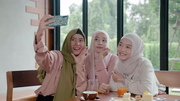 group of Muslim girls dining in a restaurant is using their mobile phones to chat online with their