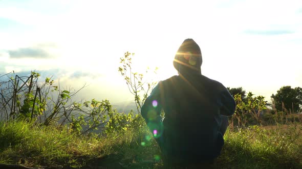 Man Hermit Meeting Up Sun Rise on the Edge of Mountains. Doing Meditation in Sun Light