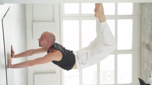 Professional Yogi Man Doing Scorpion Yoga Pose in Bright Studio Room