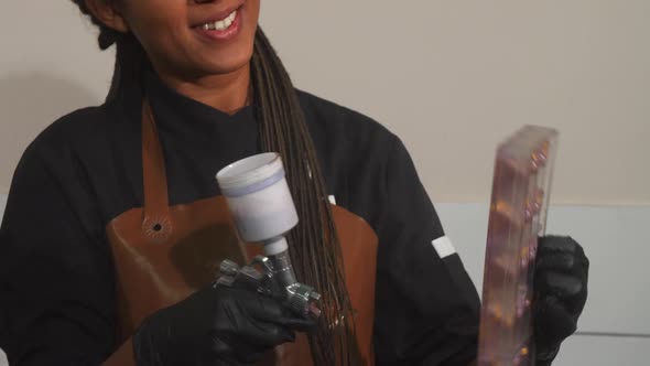 Cheerful Female Chef Using Airbrush Decorating Chocolate Mold alt