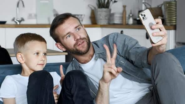 Young father spend time with son having fun using smartphone at home