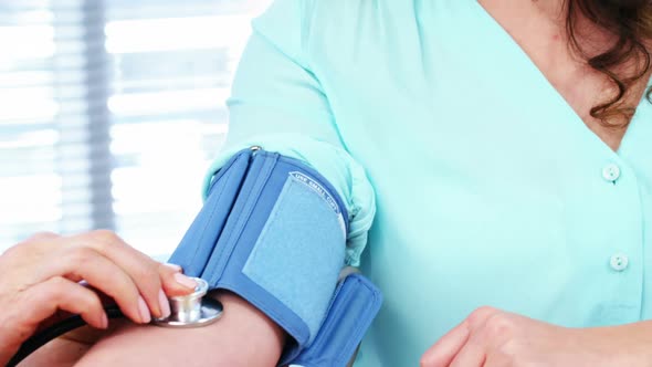 Male doctor checking blood pressure of patient alt