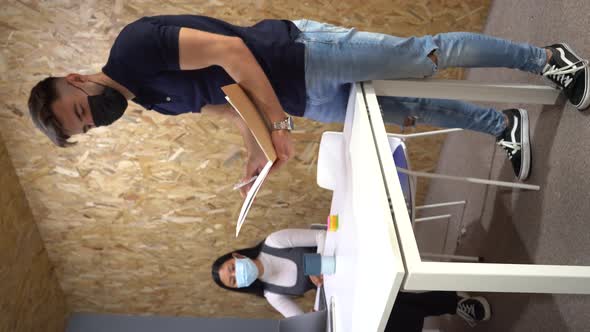 Man writing on sticky note during meeting with colleagues alt