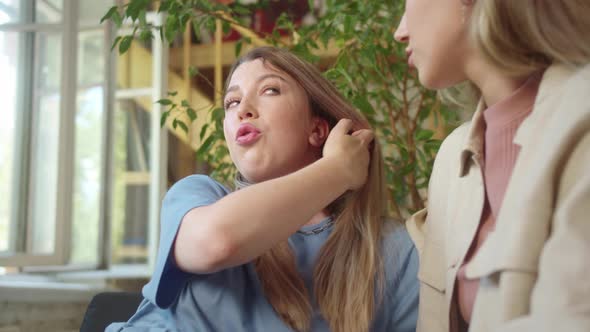 LGBT Women Sit Together in the Living Room Talk to Each Other Smiling and One of Them Touches Her alt