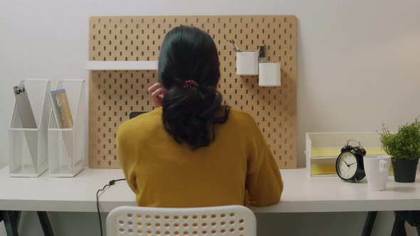 Young Asian female working on a laptop in her home office during pandemic quarantine. alt