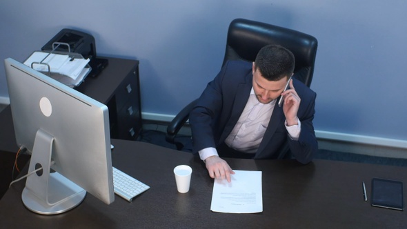 Businessman talking on phone and working on computer in office
