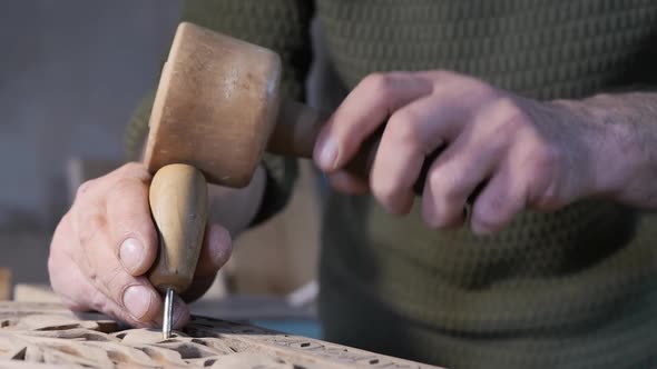 Male Hands of a Wood Carving Master Holding a Wooden Hammer and a Sharp Awl with a Wooden Handle