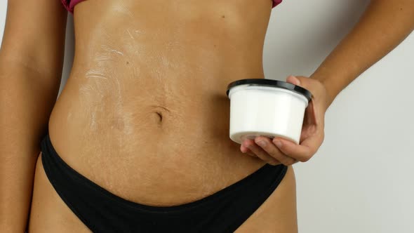 Beautiful lady smears her belly with cream. Sensitive hand massage. A woman after childbirth alt