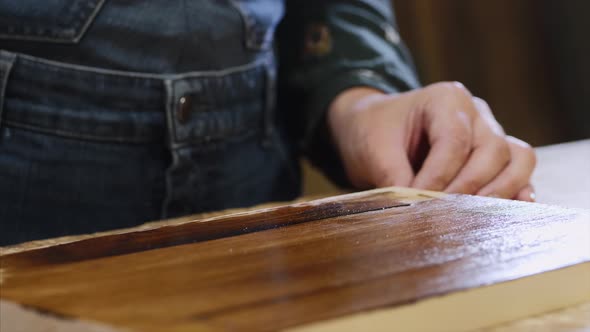 Closeup of Female Hands Is Applying of Protective Varnish on Wood Plank
