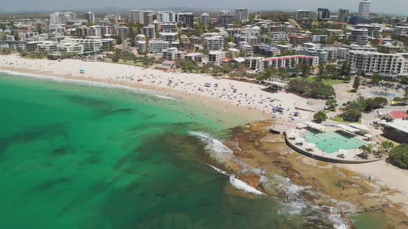 Aerial drone footage of ocean waves on a busy Kings beach, Caloundra, Australia