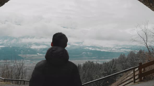 Young man with short dark hair walking through an ancient ruin arc looking into the distance with cl alt