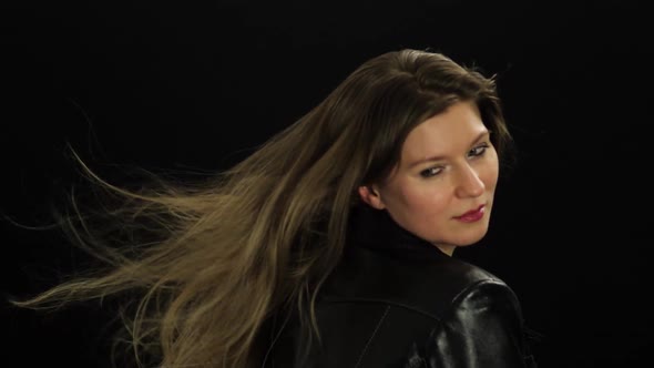 Happy blonde woman smiling on black background with the hair blowed by the wind machine alt
