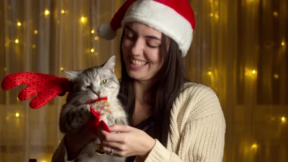 Stylish Happy Girl in Santa Hat Playing with Cute Cat