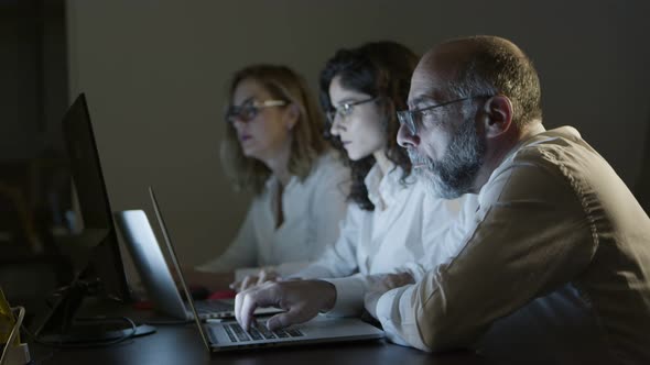 Tired Business People with Laptops in Dark Office alt