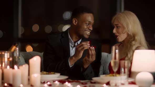 African Man Making Proposal To Girlfriend Showing Ring In Restaurant alt