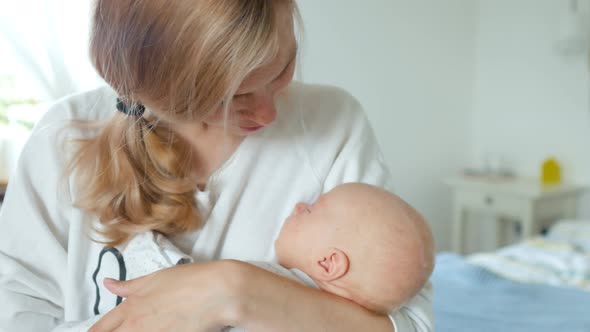 young mother gently hugs and kisses her baby