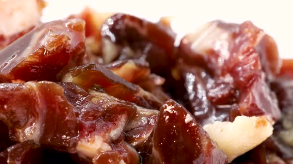 Extreme close up of fatty serrano ham pieces rotating on a white surface. Macro shot in 4k. alt