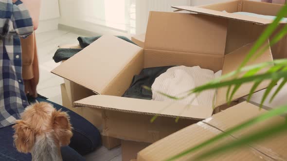 A Woman Puts Clothes in Cardboard Boxes Moving to a New House or Apartment