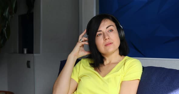 Cheerful Woman with Headphones and Smartphone Listening to Podcast alt