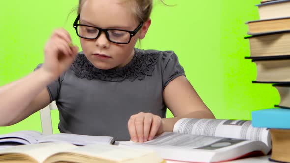 Little Girl in Glasses Looking in Books Information. Green Screen alt